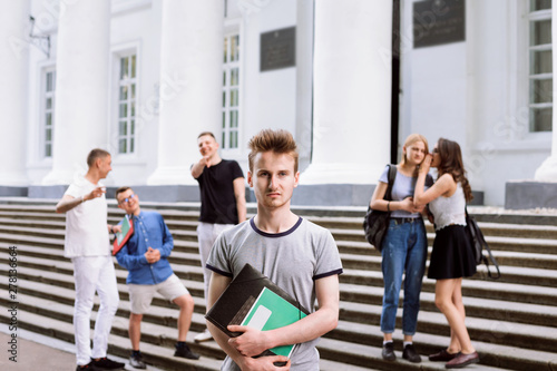 Poor male student is being mocked and sneered by his group mates during break in university campus. Concept of bullying between classmates at school or university