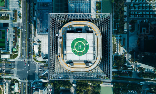 Aerial drone view of helipad on the roof of a skyscraper iin downtown with cityscape view on sunny day