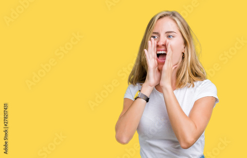 Beautiful young woman wearing casual white t-shirt over isolated background Shouting angry out loud with hands over mouth