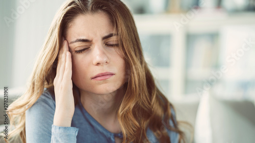 Young woman with headache in home interior