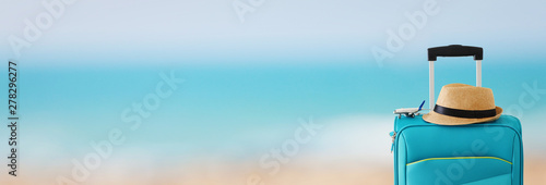 holidays. travel concept. blue suitcase and airplane toy infront of tropical sea background. banner