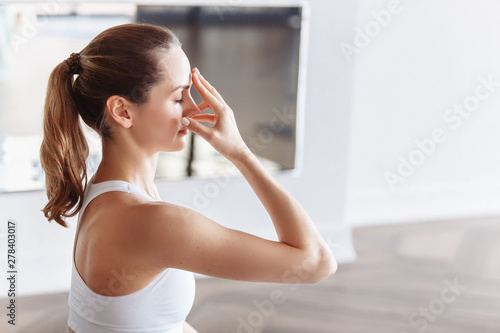 Side view of a young woman doing pranayama with her eyes closed. The concept of meditation and the rise of the kundalini