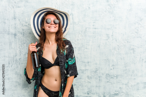 Young european woman wearing bikini and drinking a beer