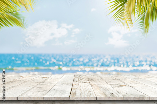 Top of wood table with seascape and palm leaves, blur bokeh light of calm sea and sky at tropical beach background. Empty ready for your product display montage. summer vacation background concept.