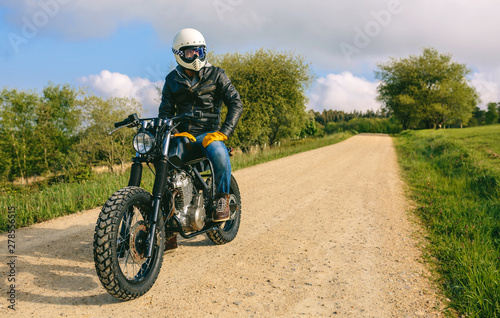 Young man with helmet riding a custom motorbike outdoors