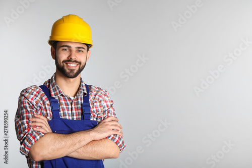 Portrait of construction worker in uniform on light background, space for text