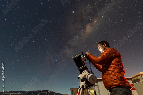 One astronomer man looking the night sky through an amateur telescope and taking photos with the Milky Way rising over the horizon, an amazing night view at Atacama Desert