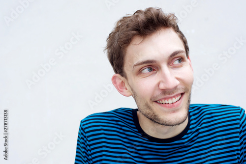 Close up young man smiling and looking away by isolated white background