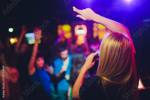 Beauty model girl singer with a microphone singing and dancing over holiday glowing background. Karaoke party singer. Disco party. Celebration.