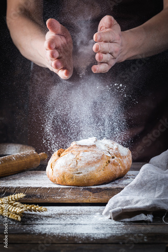 Baker cooking bread. Man slaps flour over the dough. Man's hands Making bread