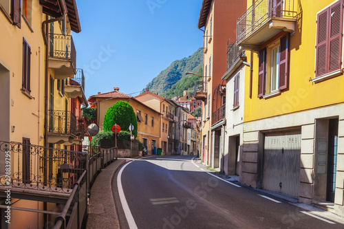 Street near of beatiful Lake Como in Lombardy, Italy. Scenic small town with traditional houses and clear blue water. Summer tourist vacation on rich resort with harbour. Nice swans