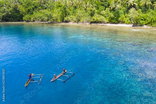 Villagers paddle their outrigger canoe in the warm, blue waters surrounding the island of New Britain in Papua New Guinea. This area is part of the Coral Triangle due to its high marine biodiversity.
