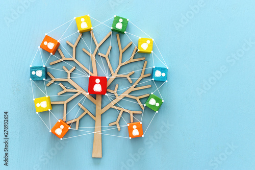 Business image of wooden tree with people icons over blue table, human resources and management concept