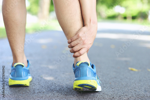 Runner touching painful twisted or broken ankle. Athlete runner training accident. Sport running ankle sprained sprain cause injury knee. and pain with leg bones while run in outdoor the park. 