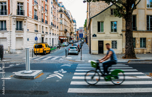 Unidentifiable man cycling down the street. The public bike system in Paris