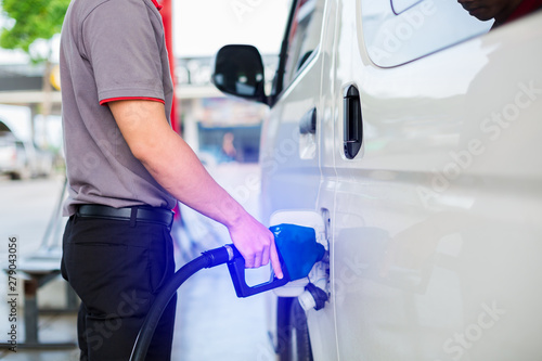 Hand refilling the white van with fuel at the gas station. Oil and gas energy.