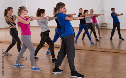 positive teenage boys and girls learning in dance hall