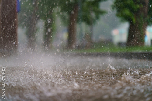 Raining day in the city at summer time. Texture of strong, fresh and powerful water drops and sprays. Puddle with ripple on Mocow road. Power, energy in nature