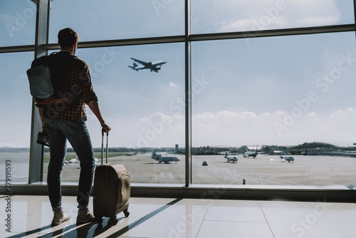 Man is watching plane flying from airport