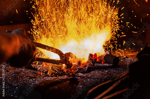 Unrecognizable Hands of Smith Preparing Metal on Anvil for Forging with spark fireworks