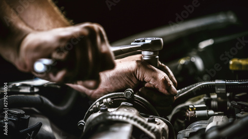 Auto mechanic working on car engine in mechanics garage. Repair service.