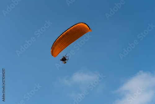 Paraglider flying over sea.Paraglider flies orange paraglider in the blue sky. Paragliding.