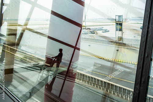 Male person silhouette reflecting in Airport terminal window - tourism and travel concept