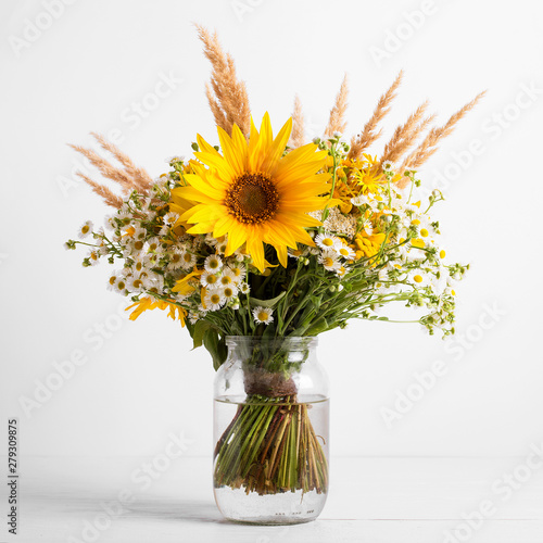 Field flowers in a glass vase. Summer bouquet of flowers on the white background