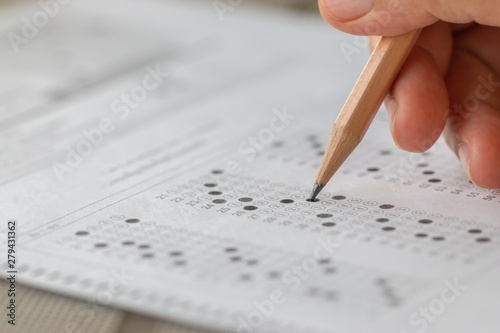 Student hand testing doing test exam with pencil drawing selected choices on answer sheet in school final exams at college or university. Taking multiple choice for assessment in examination classroom