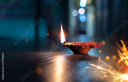 Happy Diwali - Lit diya lamp on street with firecrackers