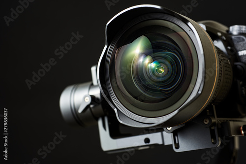 Close-up of wide angle lens in a dsl camera and gimbal stabilizer, with low-key lighting and a black background