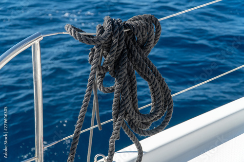balck mooring lines hanging on the reeling on a sailing yacht