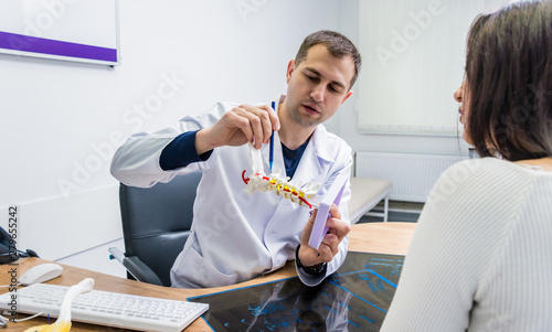 Orthopedist showing spine model to patient in hospital