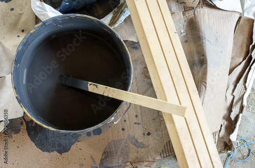 Mixing paint in a bucket with a wooden stick