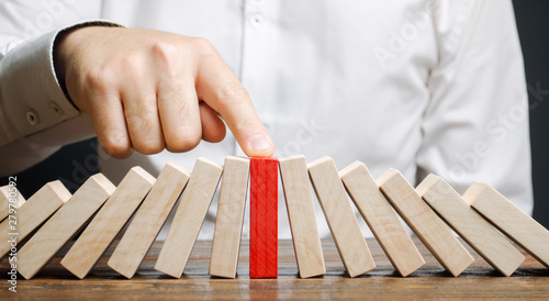 Businessman stops collapse domino effect. Stress resistance business. Financial stability. Recovery business. Evaluation of cash risks. Creating a strategy. Management and planning. Decision making