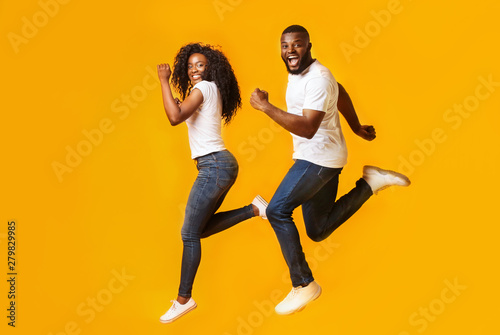 Joyful afro man and woman are running in the air