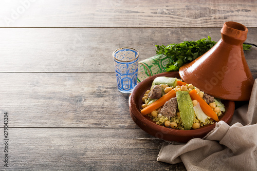 Traditional tajine with vegetables, chickpeas, meat and couscous on wooden table. Copyspace