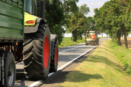 Ciągmik rolniczy, traktor i kombajn na drodze asfaltowej w słoneczny dzień.