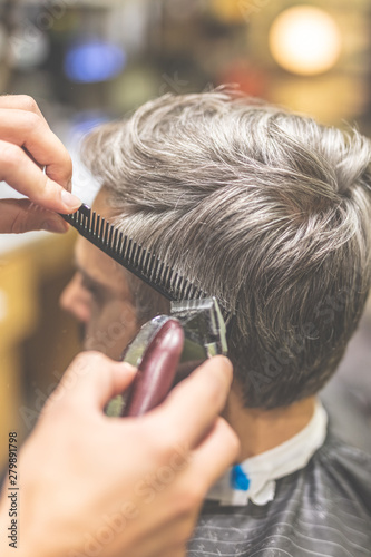 Barbershop. Hairdresser does hairstyle with hair clipper and comb.