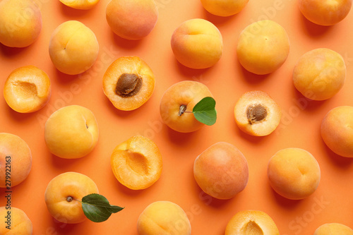 Delicious ripe sweet apricots on orange background, flat lay