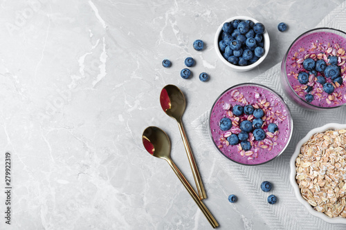Tasty blueberry smoothie served on grey table, flat lay. Space for text