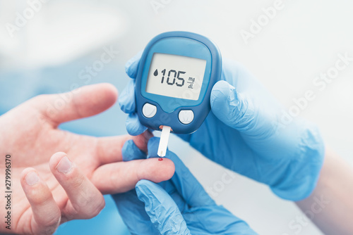 Doctor checking blood sugar level with glucometer