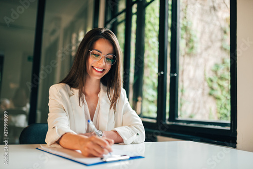 Smiling elegant businesswoman or student filling application form.