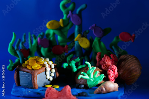 Plasticine underwater landscape. The ocean and the undersea world background, corals and open pirate chest with shinny gold.