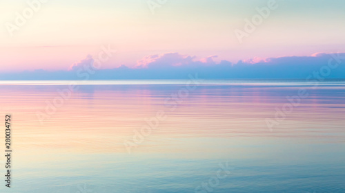 Morning clear seascape with colorful sky. Natural soft background. Beautiful magical pink and gold reflected in the water.