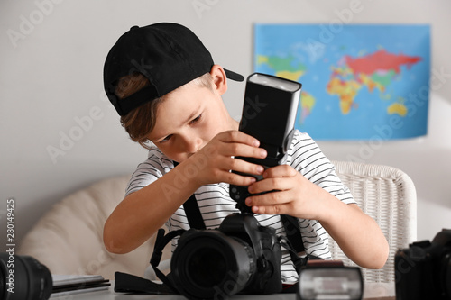 Cute little photographer with professional camera at home