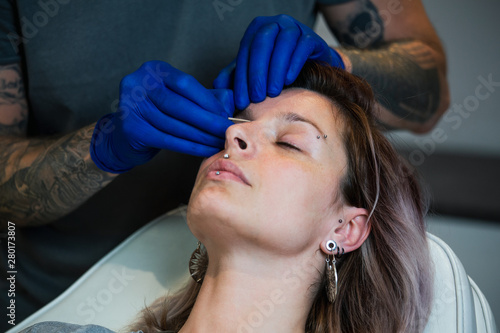 Man showing a process of piercing with steril medical equipment and latex gloves. Marking the piercing spot. Body Piercing Procedure