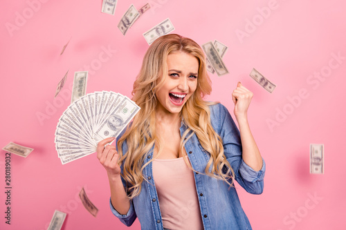 Pretty lady holding bucks bills flying everywhere wear denim outfit isolated pink background