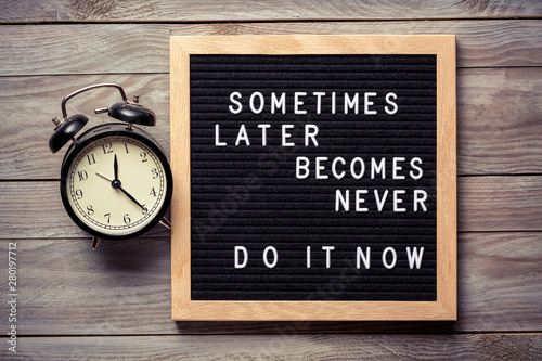 Inspirational motivational quote Sometimes later becomes never. Do it now words on a letter board on wooden background near vintage alarm clock. Success and motivation concept.