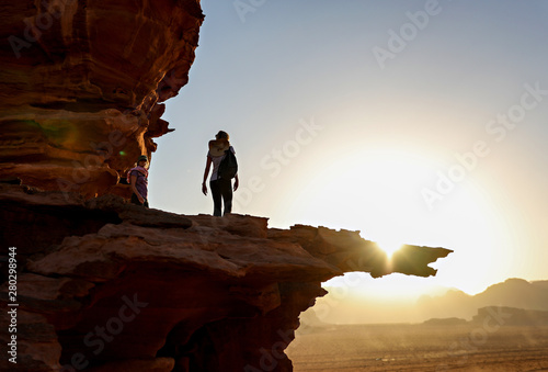 Woman hiking on a ledge at sunset, silhouette.